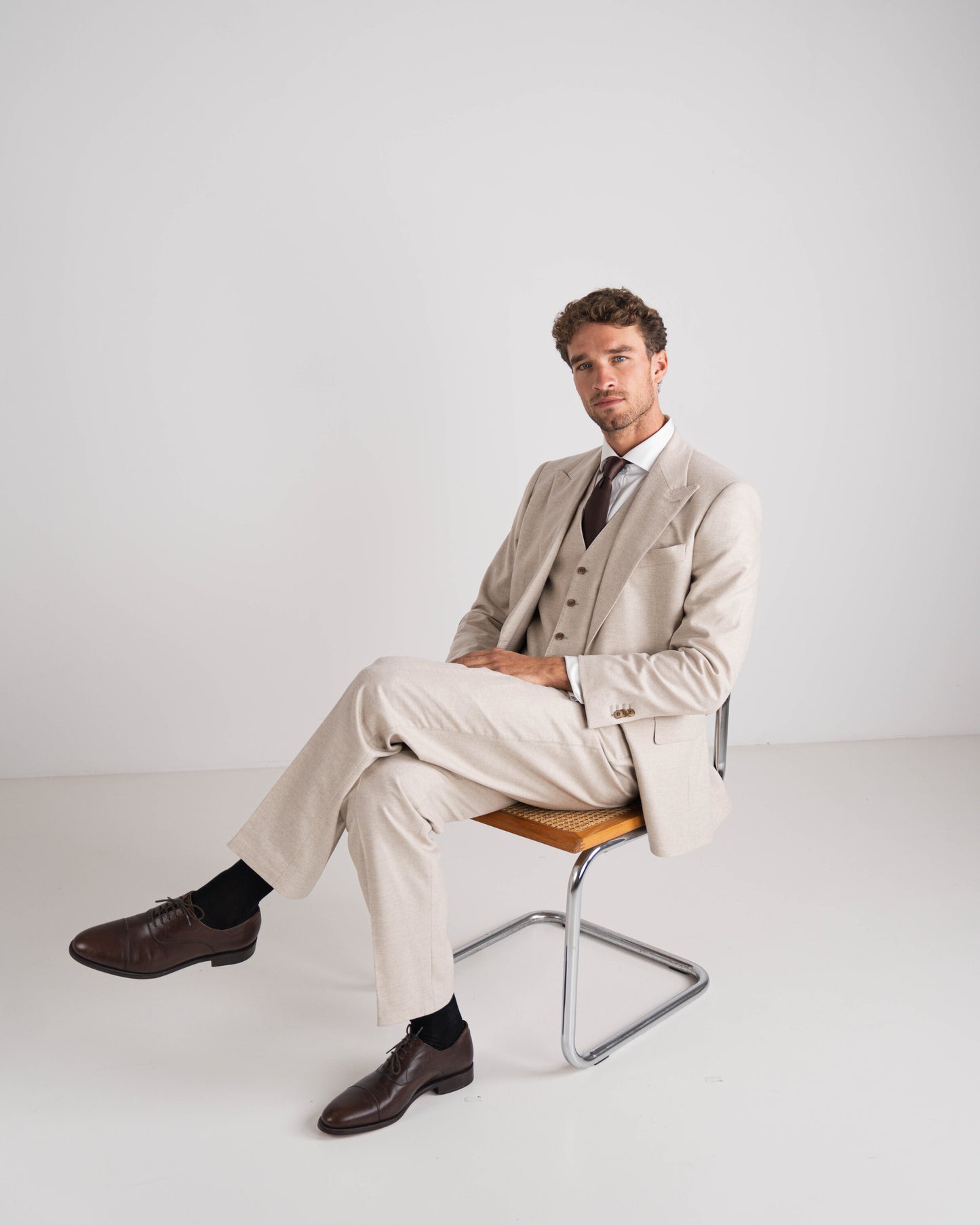 Man in beige drie delig kostuum met bruine das