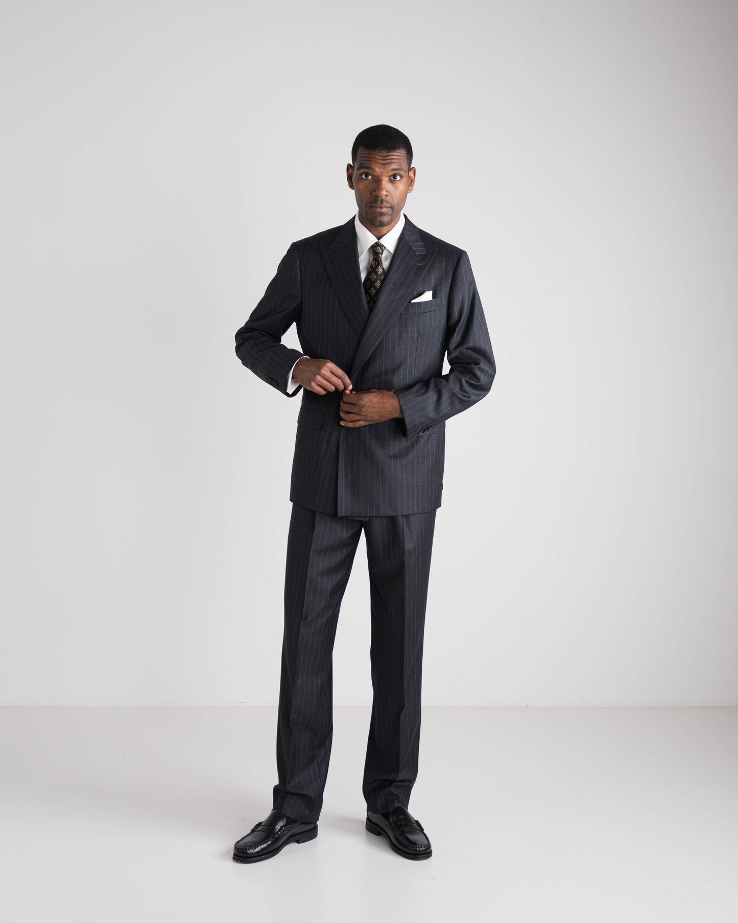 Man wearing a dark pinstripe suit on a white background