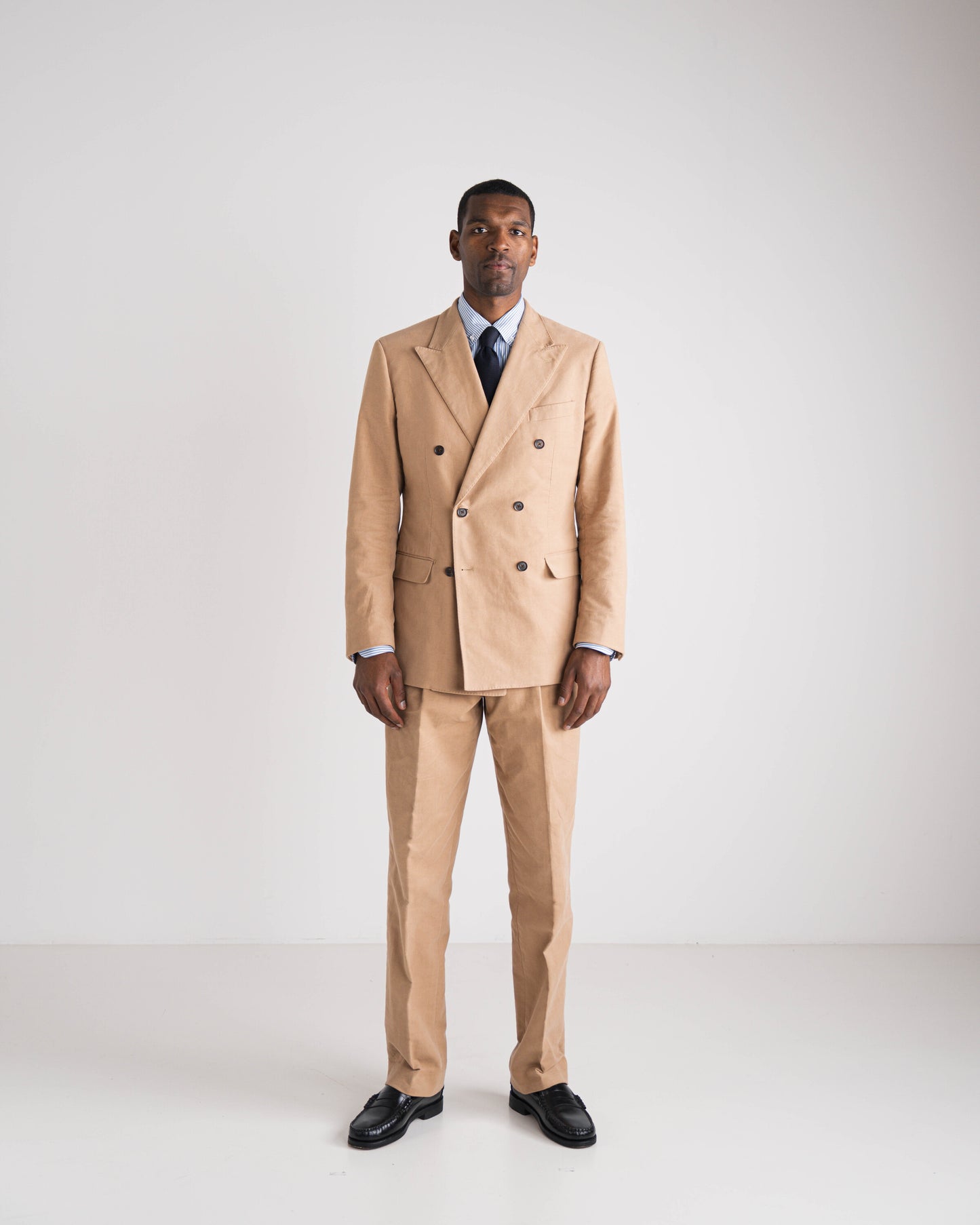 man in camel double breasted kostuum met blauwe das