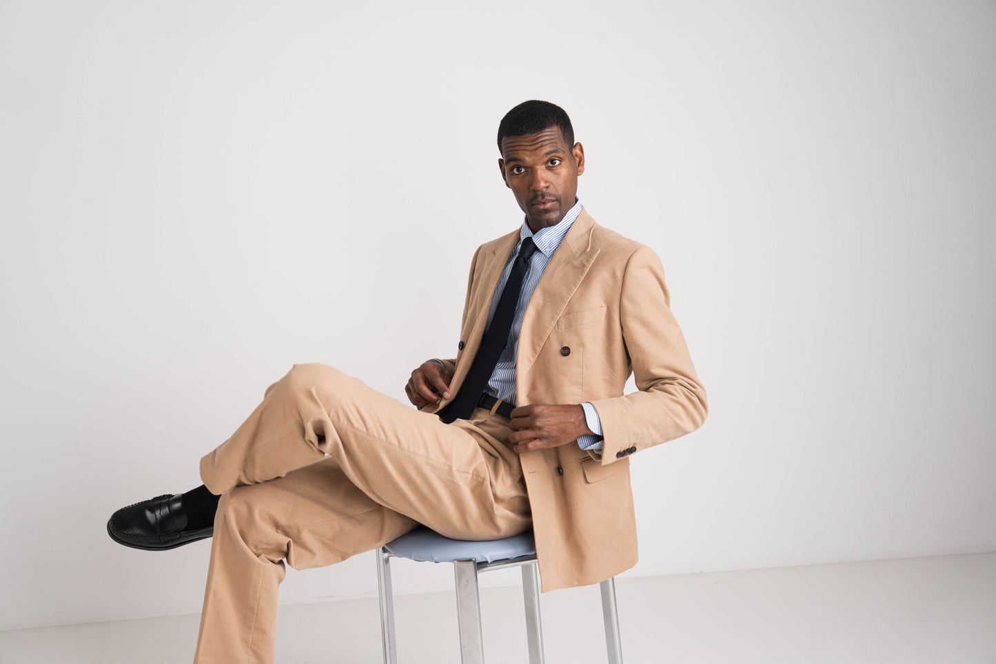 man in camel kostuum met blauwe das en blauw hemd