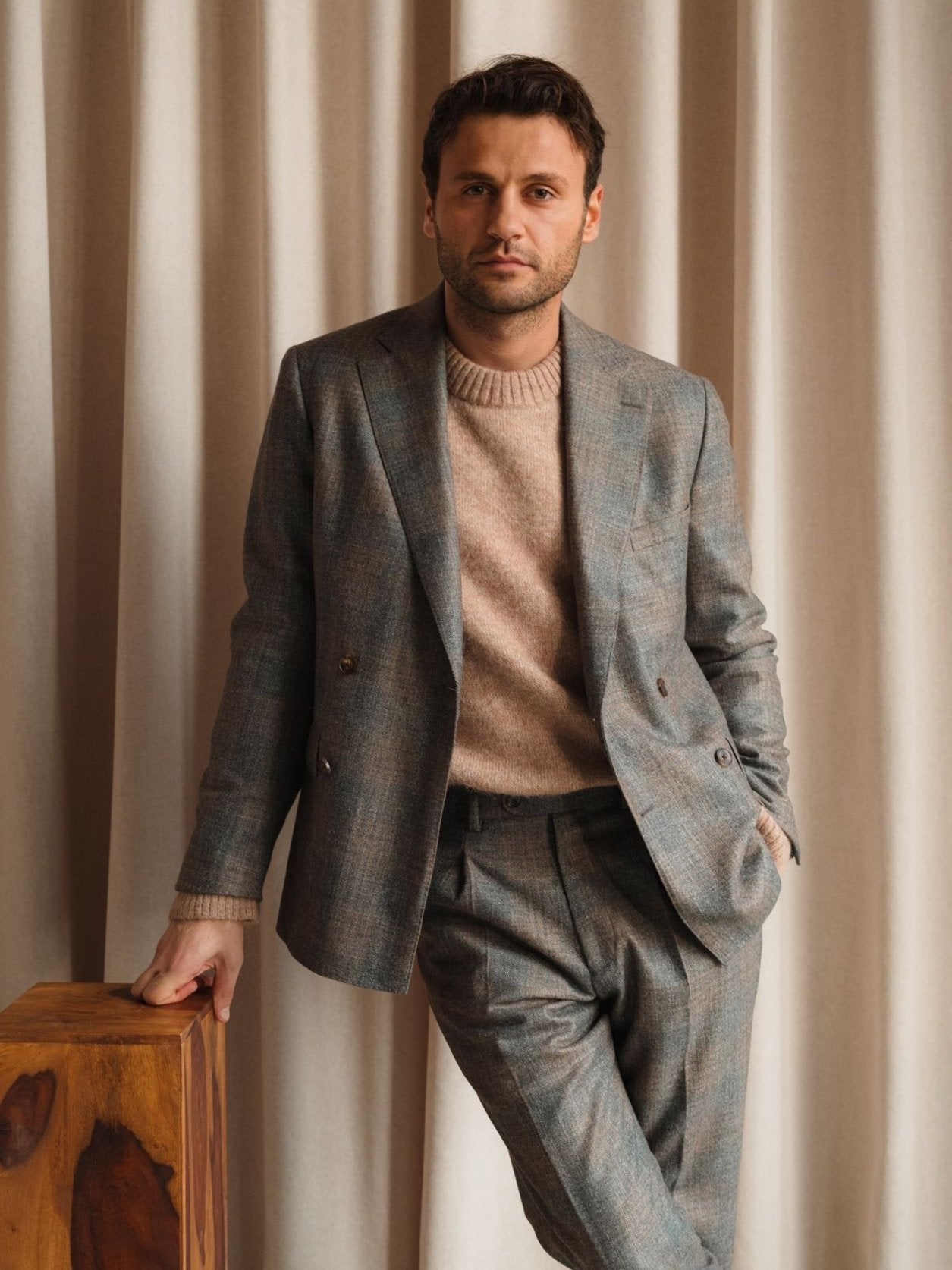 Hakan Can, founder of Atelier ACÀN, wearing a bespoke suit with grey-blue textured fabric and soft knit underneath. Tailored in Ghent and Antwerp.