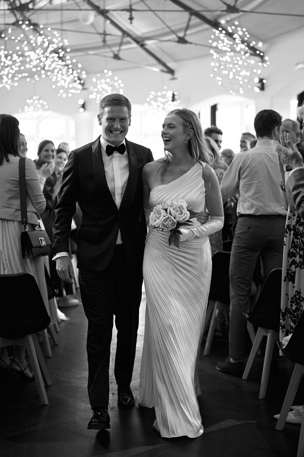 Newlywed couple celebrating, groom in a handcrafted Atelier ACÀN tuxedo.