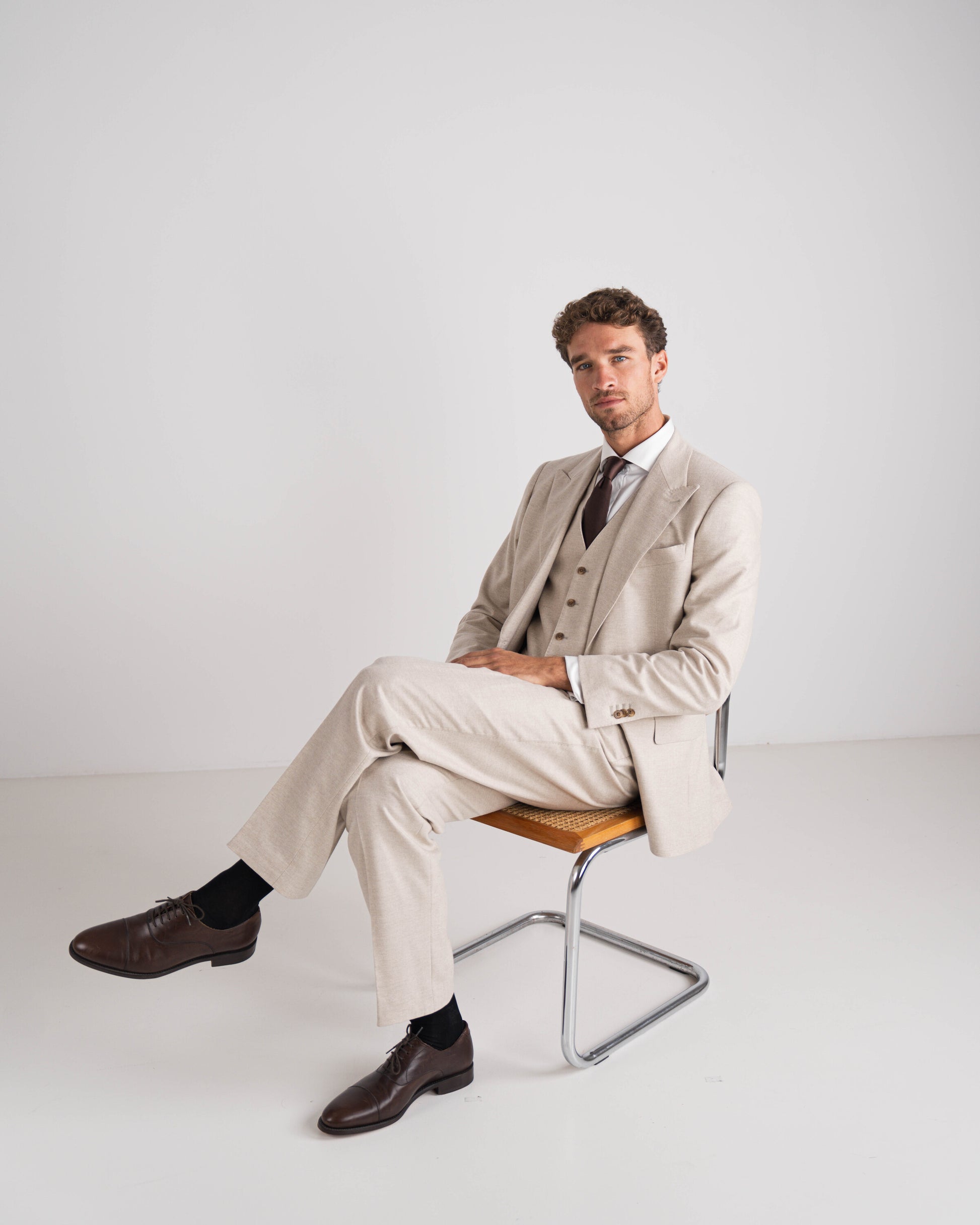 Man in beige drie delig kostuum met bruine das