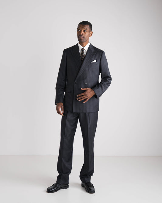 Man wearing a dark gray suit with a white shirt and patterned tie on a white background