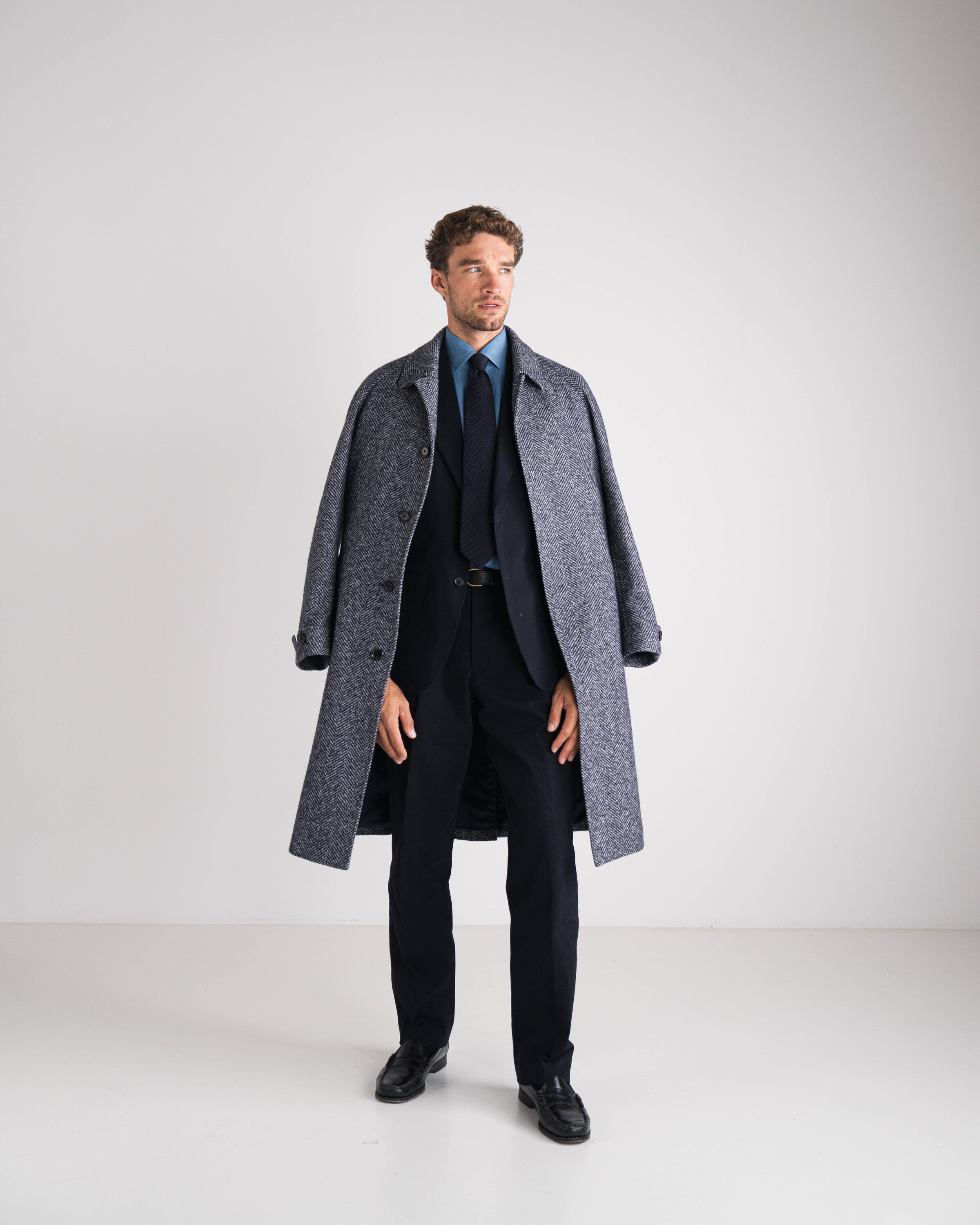 man in blauw kostuum met grijze wintermantel en blauwe das