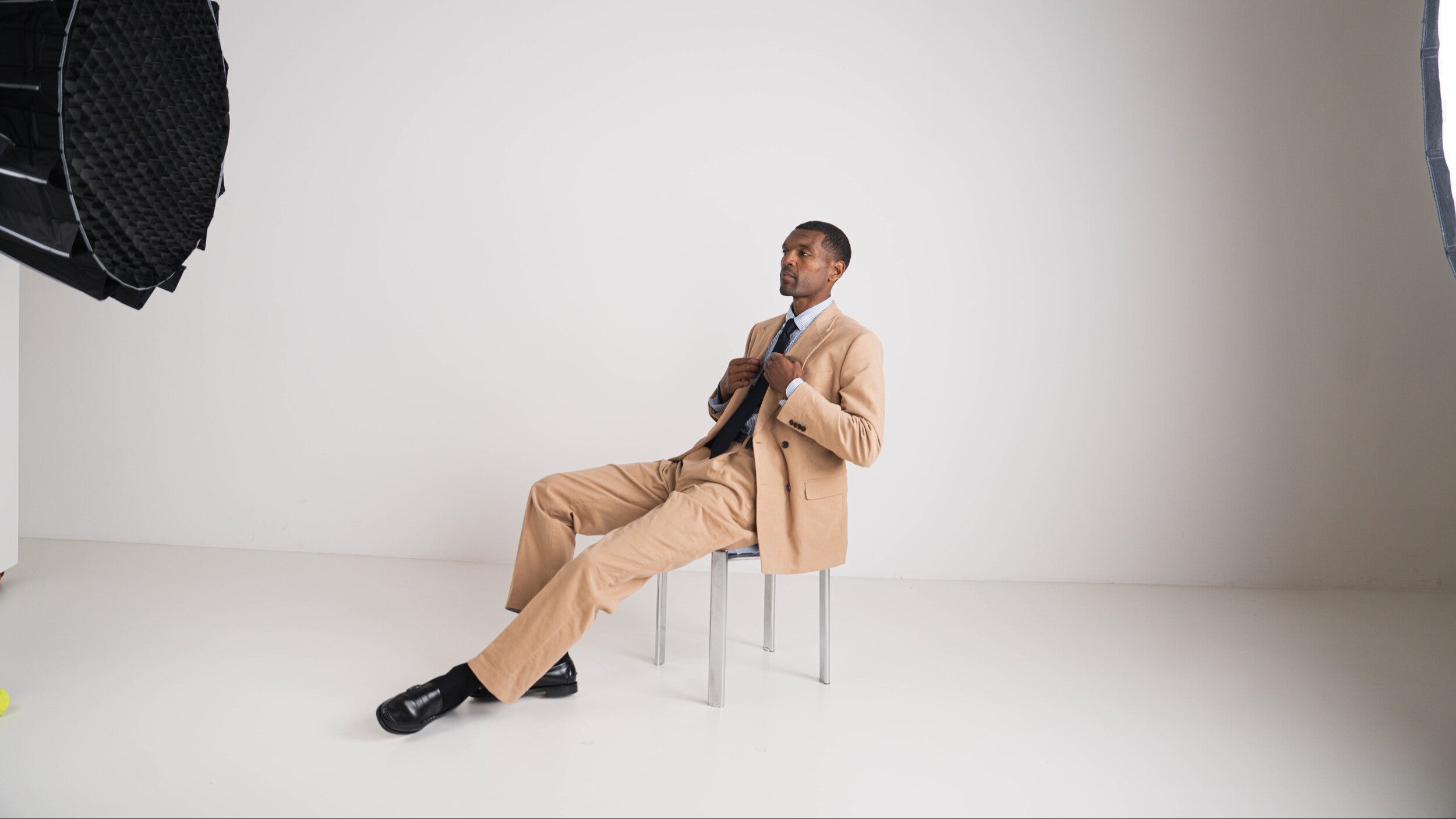Man in beige maatpak in studio met professionele belichting