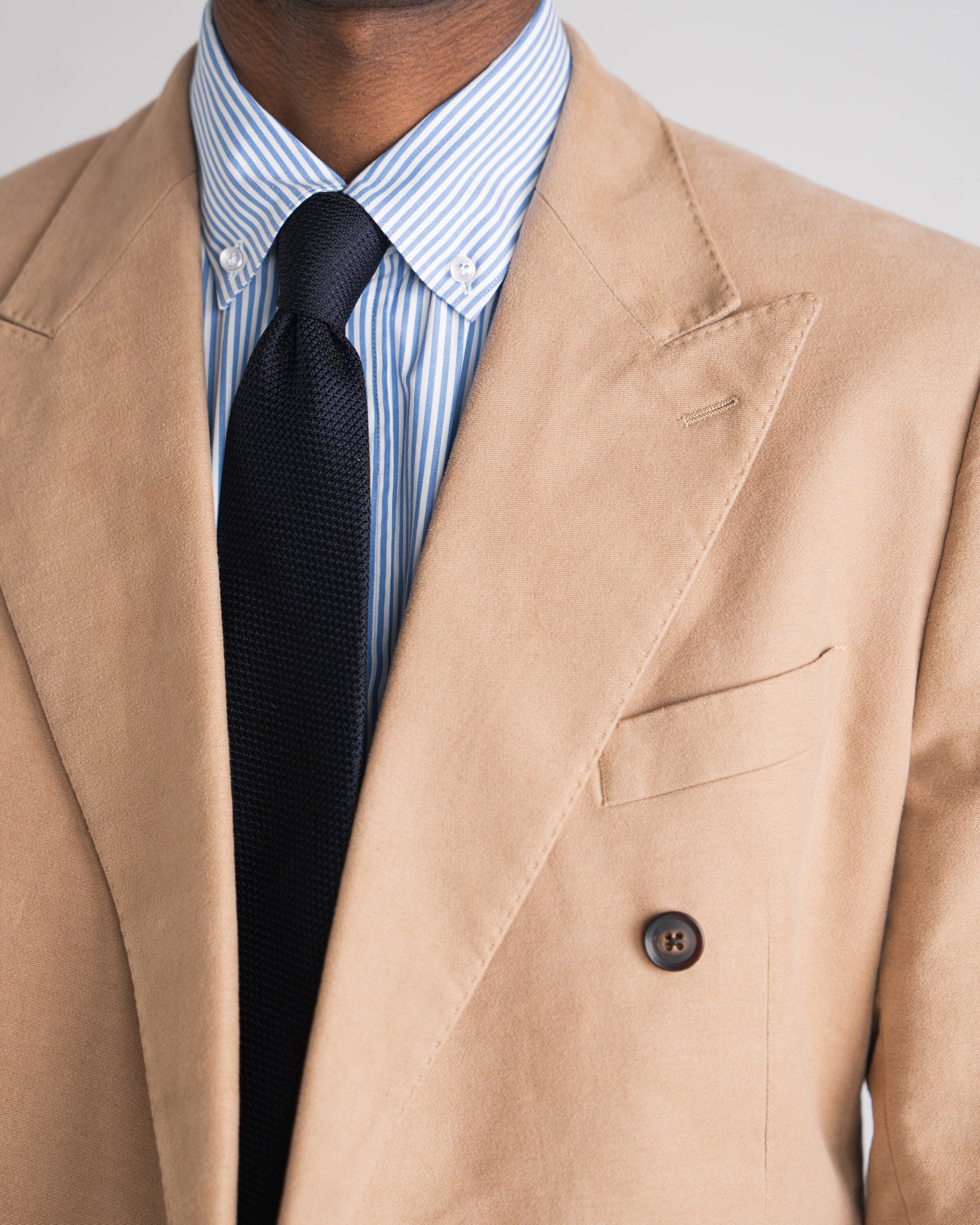 man in camel kostuum met blauw gestreept hemd en blauwe das